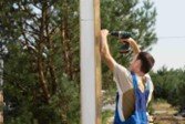 Technician performing post replacement with power tools during fence repair in Rockwall, TX.