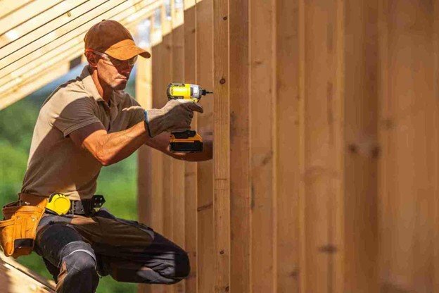 Builder securing cedar fence boards with a drill, aligning each panel for a straight installation.