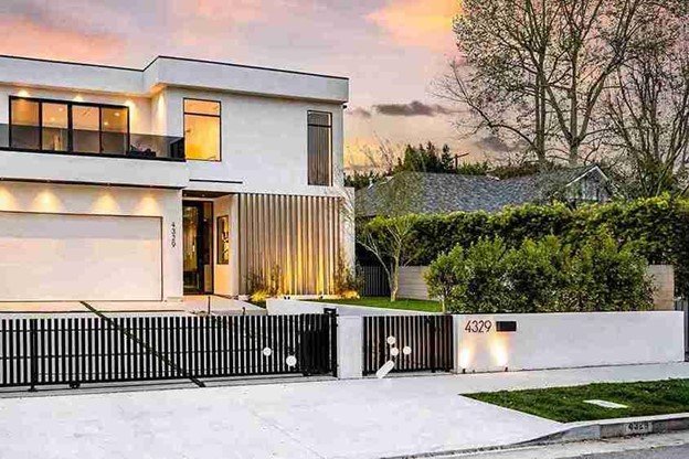 Modern metal gate installed in front of a contemporary home with outdoor lighting at sunset.